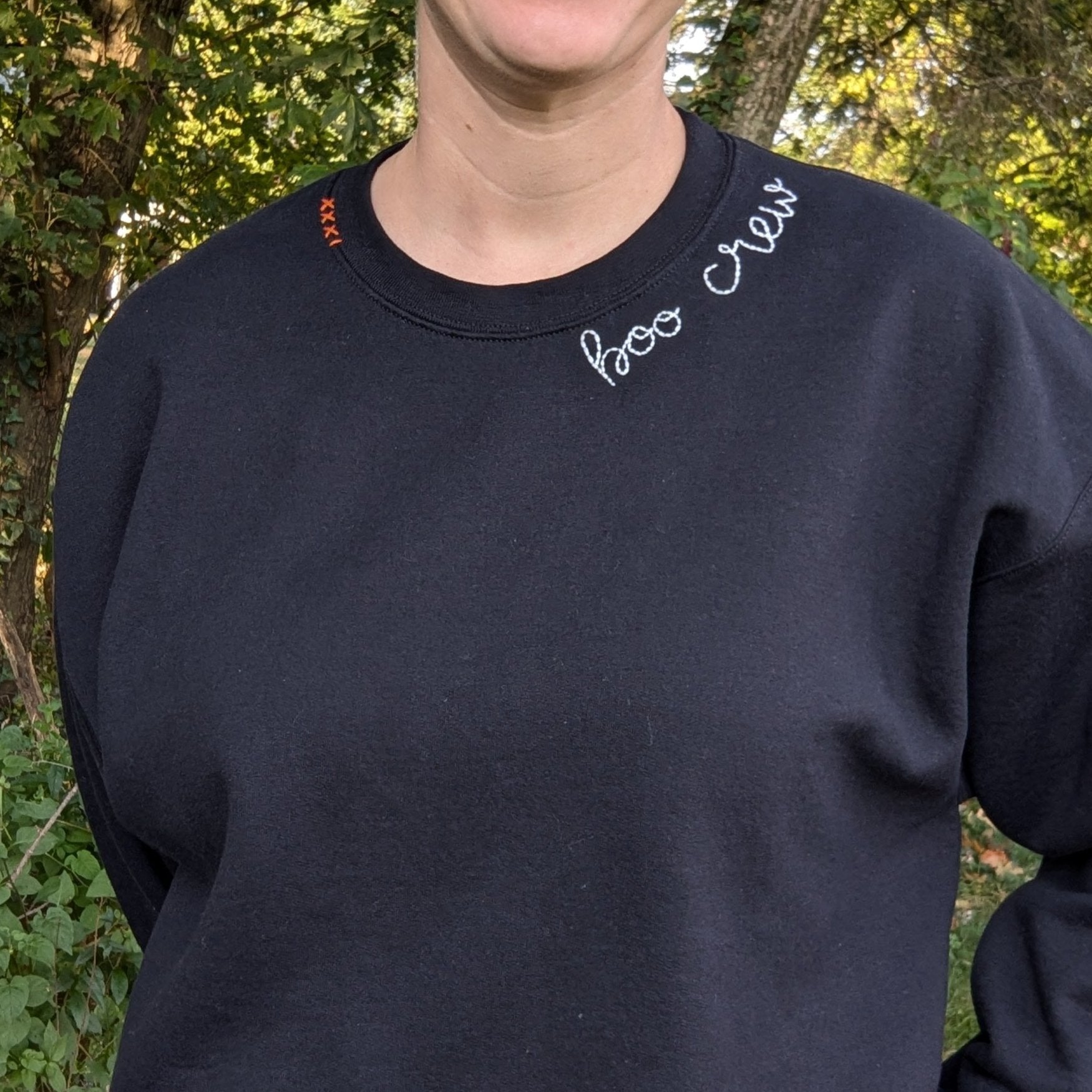 Black crewneck sweatshirt with white hand embroidered boo crew at neckline orange Roman numerals 31 on opposite collar