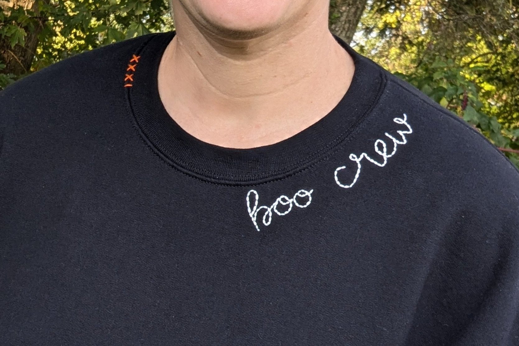 Black crewneck sweatshirt with white hand embroidered boo crew at neckline orange Roman numerals 31 on opposite collar